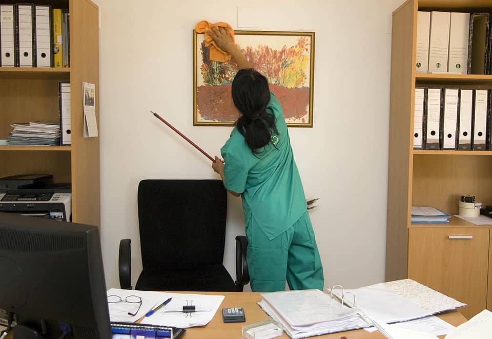 janitor wiping the picture on the wall in the office